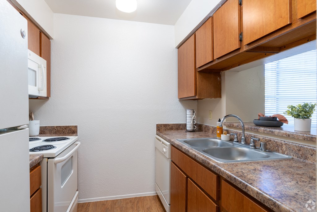 A kitchen with a white refrigerator, a white stove, and a brown counter.