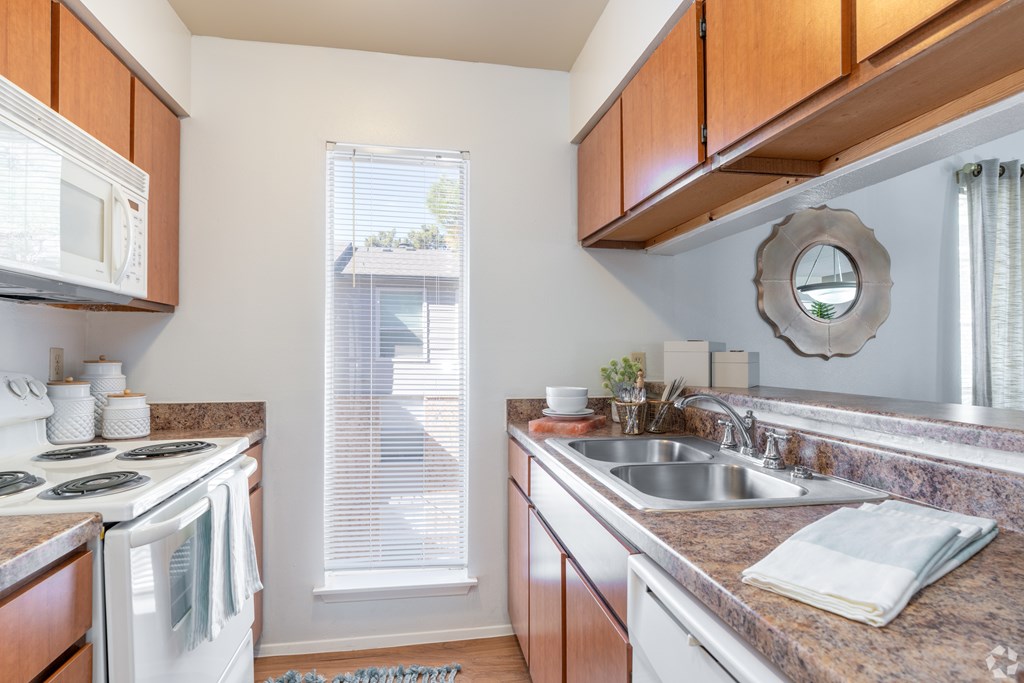 A kitchen with a white stove top oven and a white microwave.