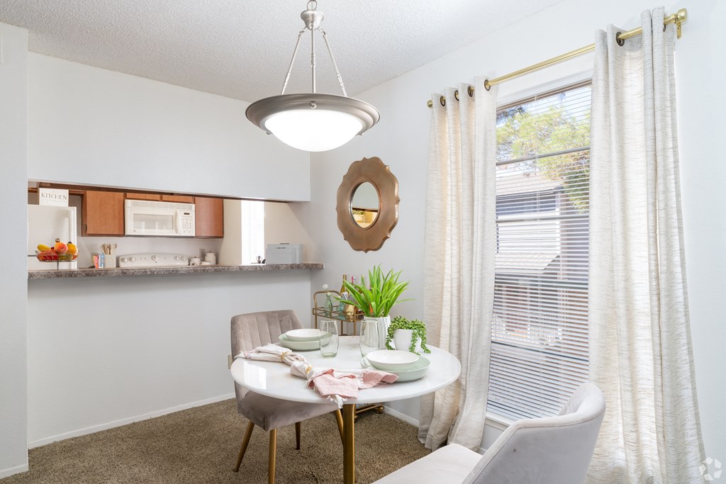 A dining room with a table set for two and a potted plant on the table.