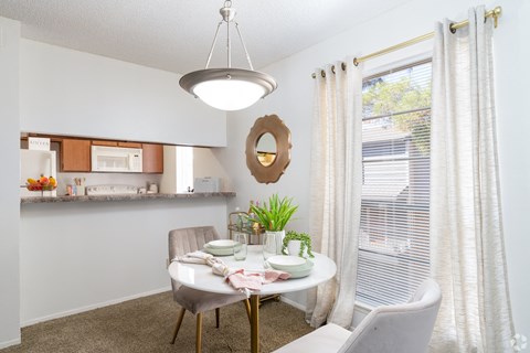 A dining room with a table set for two and a potted plant on the table.