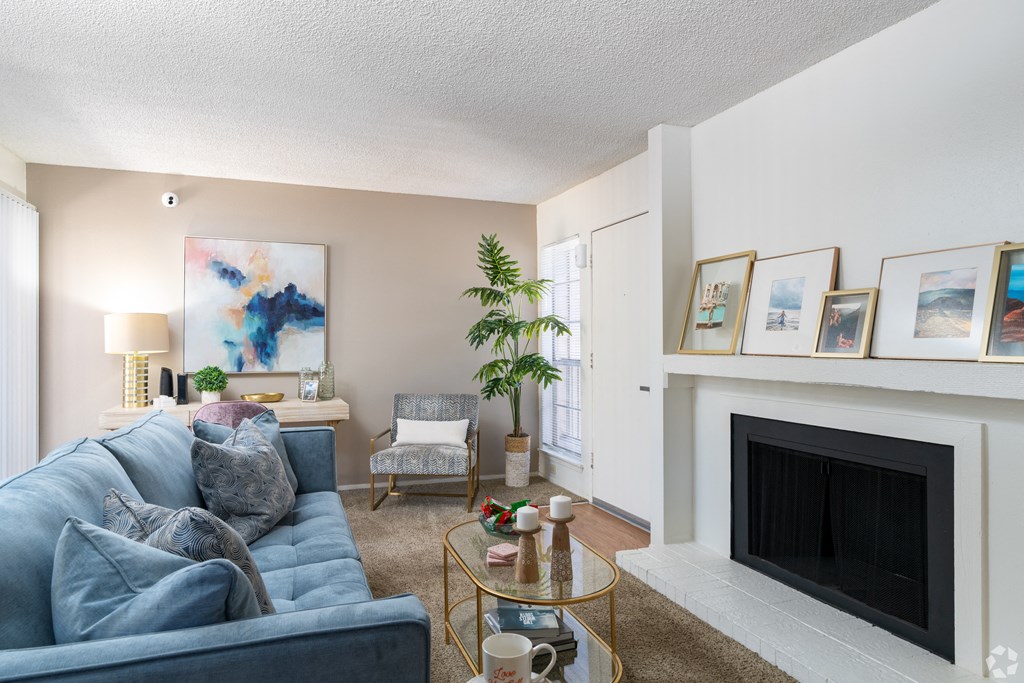 A living room with a blue couch, a fireplace, and a painting on the wall.
