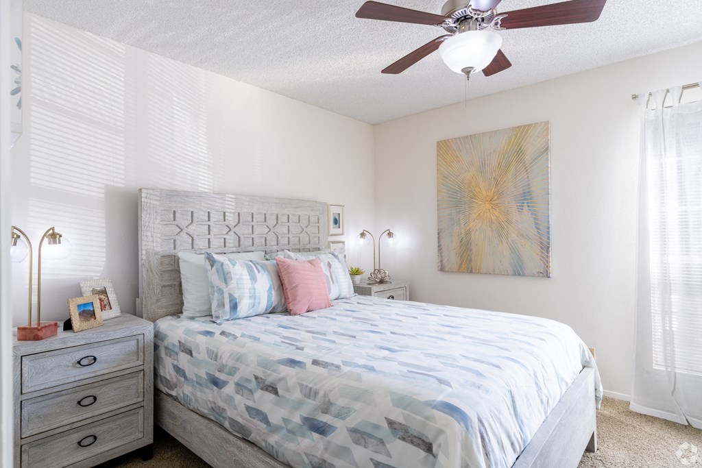 A bedroom with a bed, nightstand, and a painting on the wall.