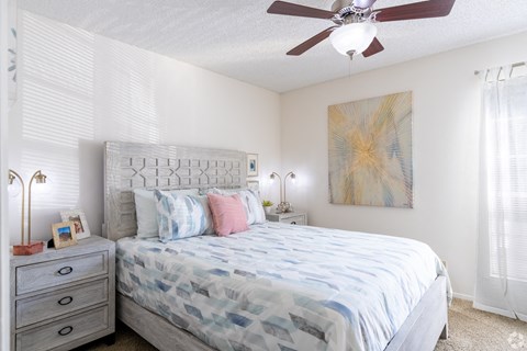 A bedroom with a bed, nightstand, and a painting on the wall.