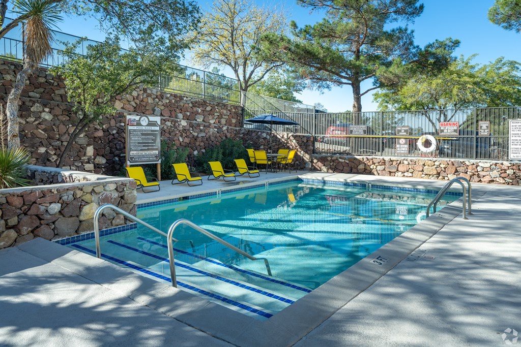 A pool with a signboard and yellow sun loungers.