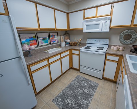 A kitchen with a refrigerator, microwave, oven, and sink.