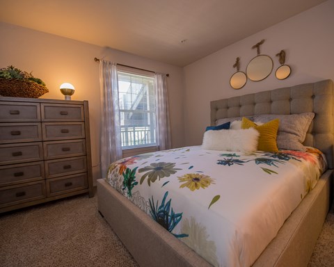 A bedroom with a large bed and a window with curtains.