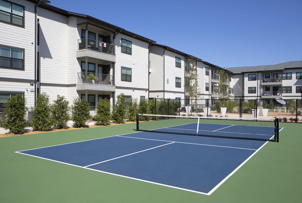 a tennis court with apartments in the background
