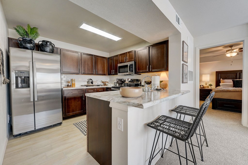 a kitchen with stainless steel appliances and a counter with two bar stools