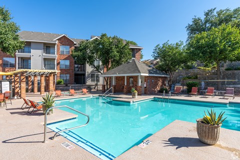 A swimming pool surrounded by chairs and a small building.