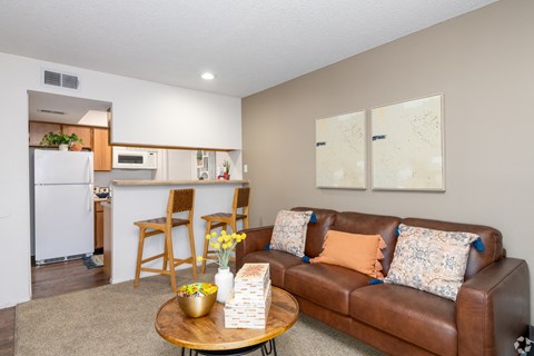 A brown leather couch with a coffee table in front of it.