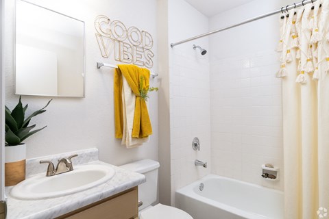 A bathroom with a white tub, sink, and a yellow towel.