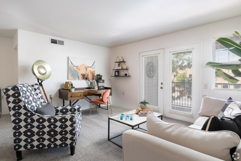 A living room with a patterned chair, a white couch, and a painting of a bull on the wall.