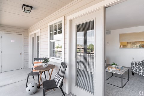A small balcony with a table and chairs.