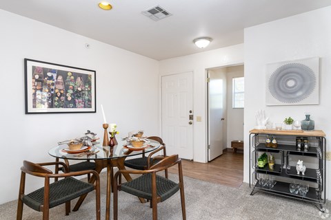 A dining room with a table set for two and a painting on the wall.