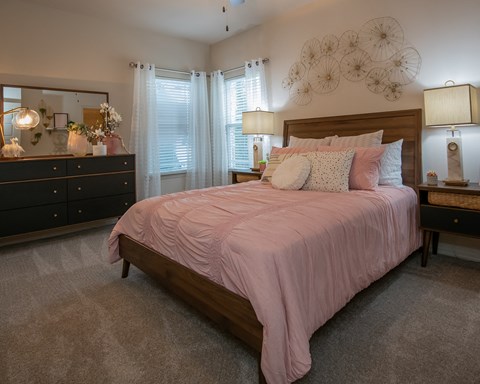A bedroom with a large bed and a dresser with a mirror.