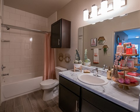 A bathroom with a white sink, a white toilet, a white bathtub, and a brown cabinet.