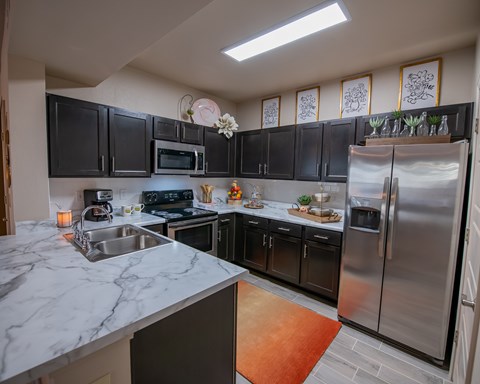A kitchen with black cabinets and a marble countertop.