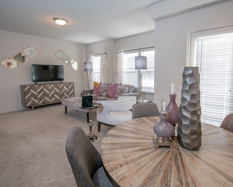 A modern living room with a wooden table and grey chairs.
