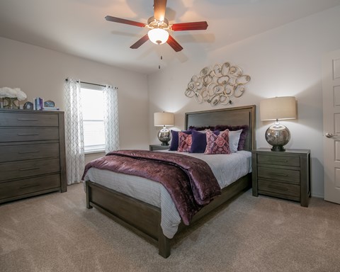 A bedroom with a large bed and a ceiling fan.