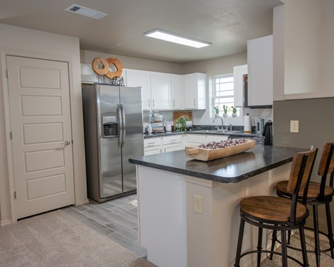 A kitchen with a black countertop and a white fridge.