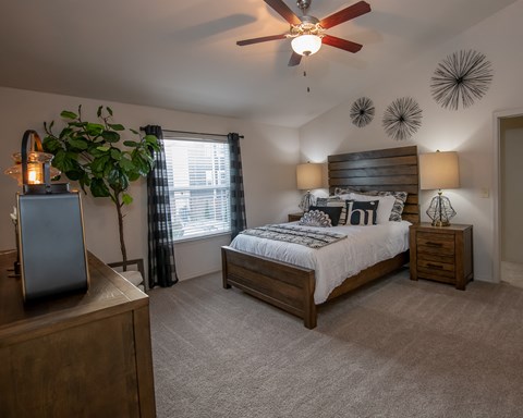 A bedroom with a bed, nightstand, and a ceiling fan.