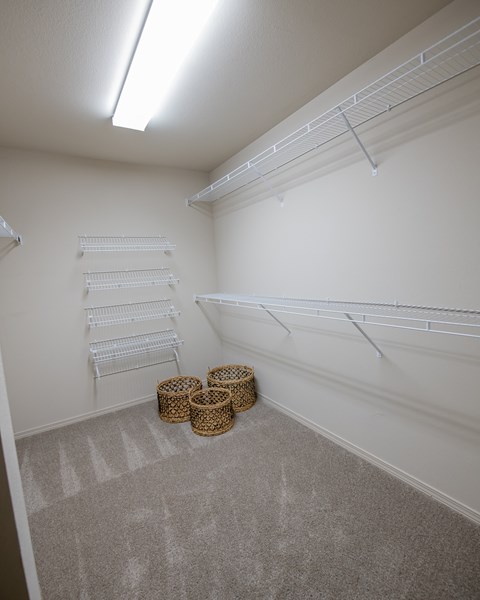 A room with white walls and a carpeted floor with three baskets on it.
