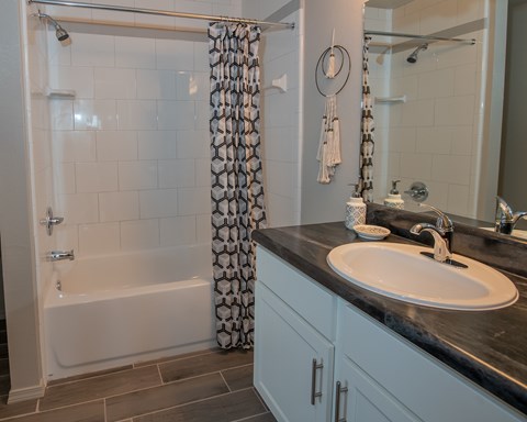 A bathroom with a black counter top and a white sink.