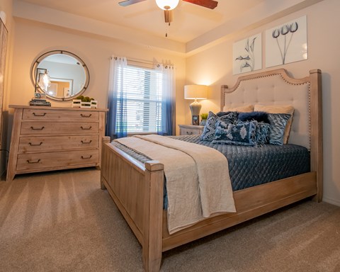 A bedroom with a large bed, a dresser, and a ceiling fan.