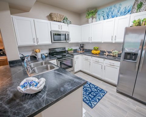 A kitchen with a black counter top and white cabinets.