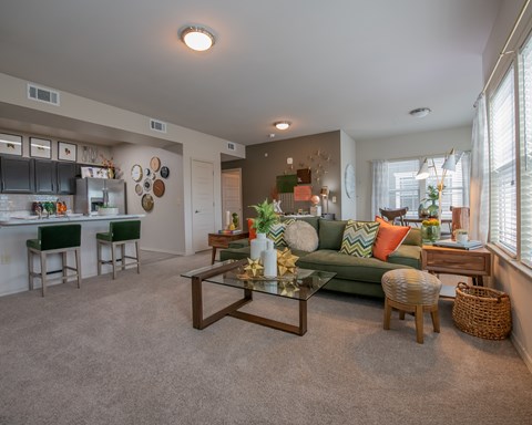 A living room with a green couch and a glass coffee table.