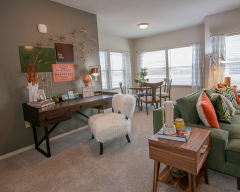 A living room with a green couch, a white dog, and a wooden coffee table.