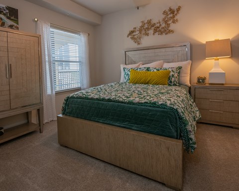 A bedroom with a bed, nightstand, and a cabinet.