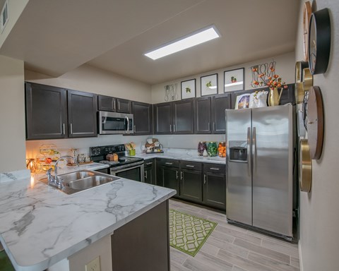 A kitchen with a marble counter top and stainless steel appliances.