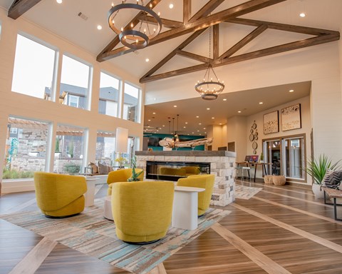 A large room with a fireplace and yellow chairs.