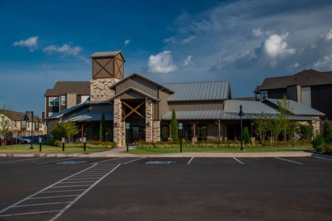 A parking lot in front of a building with a stone chimney.