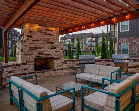 A patio with a stone fireplace and seating area.