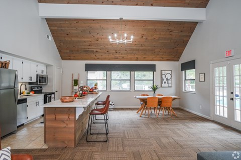 A kitchen with a wooden ceiling and a dining table with chairs.