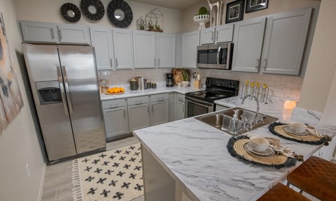 A kitchen with a marble countertop and a refrigerator.