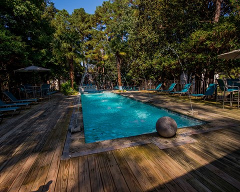 A large stone ball sits on the edge of a blue pool.