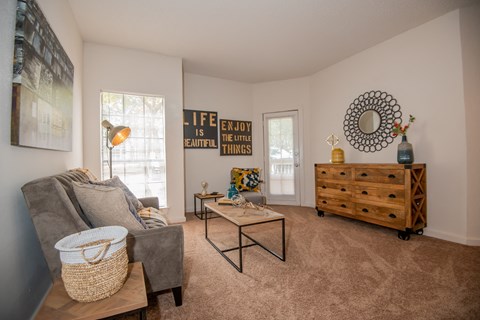 A living room with a grey couch, a coffee table, and a wooden chest of drawers.