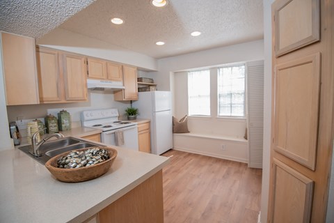 A kitchen with wooden cabinets and a bowl of clams on the counter.