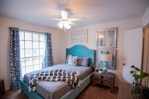 A bedroom with a bed, nightstand, and a ceiling fan.