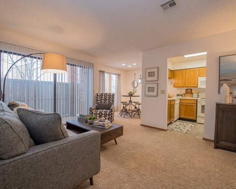 A living room with a grey couch and a chair with a leopard print cushion.