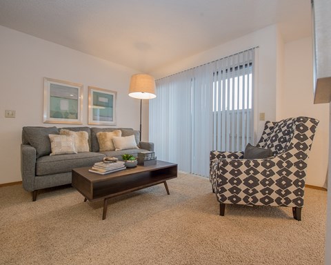 A living room with a grey couch, a coffee table, and a patterned armchair.