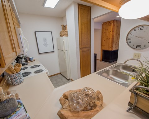 A kitchen with a white counter top and a clock on the wall.