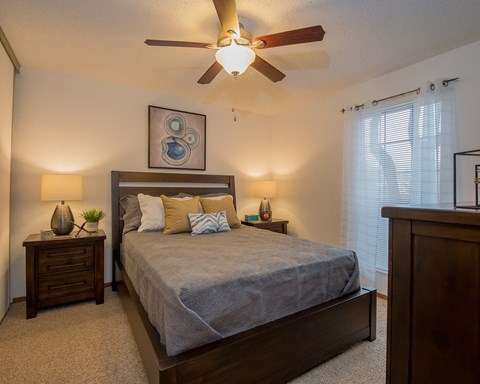 A bedroom with a bed, nightstands, and a ceiling fan.