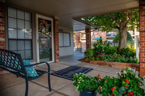 A black bench with a blue cushion is on a porch.
