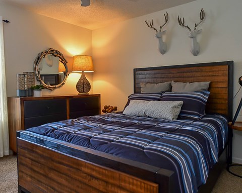 A bedroom with a bed, nightstand, and deer head wall decor.