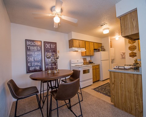 A kitchen with a table and chairs and a sign on the wall.