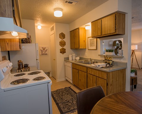 A kitchen with a white stove top oven and wooden cabinets.